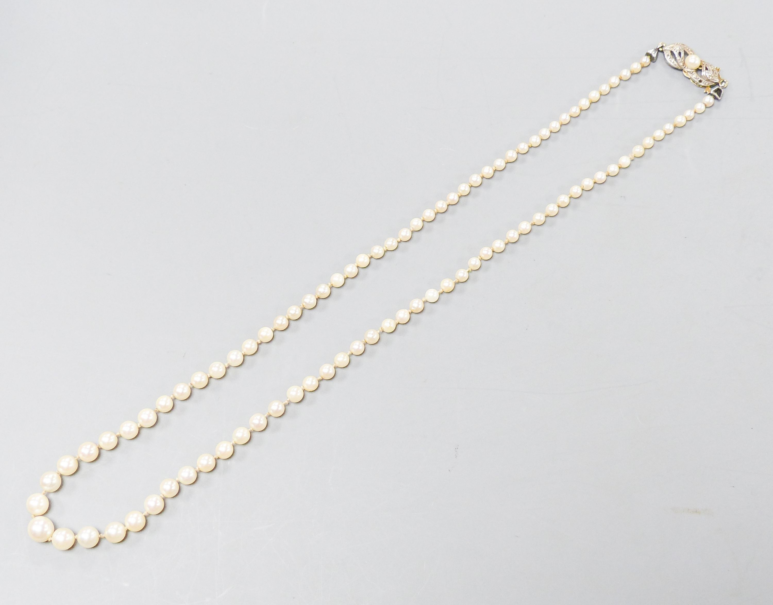 A single strand graduated cultured pearl necklace with yellow metal and gem set clasp, 49cm.